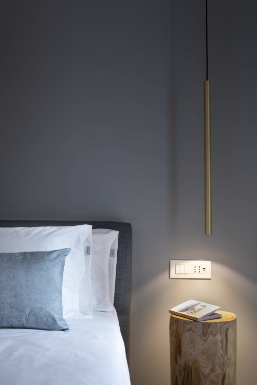 Camera moderna presso Camere d'Aria B&B a Locana con testata scura, cuscino blu, lampada a sospensione e comodino in legno