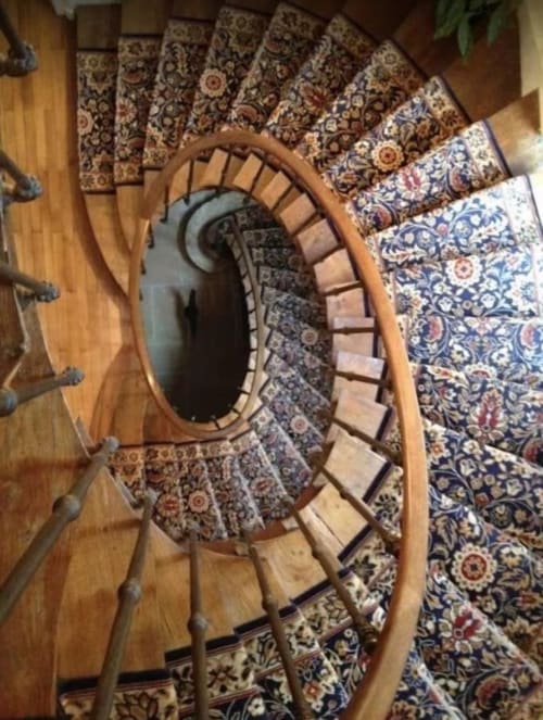 Escalier en spirale avec rampe en bois et tapis à motifs à l'hôtel Les Rives De La Tronne