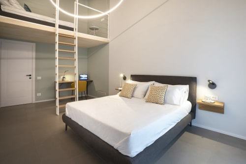 Modern bedroom with queen bed, wooden loft ladder, desk area, and mountain views at Camere d'Aria BnB in Locana, Italy