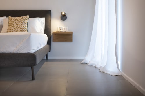 Camera moderna a Camere d'Aria a Locana con letto scuro, cuscino dorato, comodino in legno e tende bianche fluenti