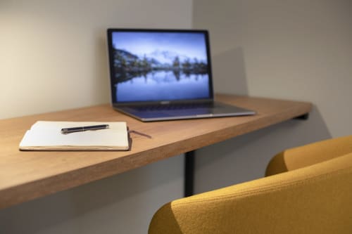 Scrivania in legno con quaderno e laptop che mostrano il paesaggio del lago di montagna presso Camere d'Aria B&B a Locana, Italia