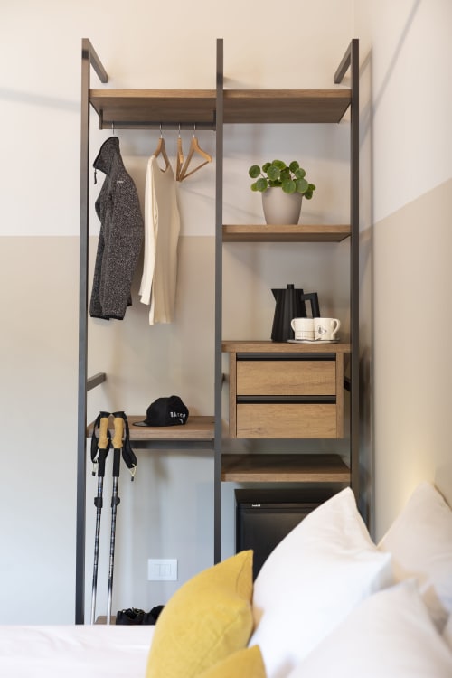 Modern open wardrobe in Locana B&B room with clothing rack, wooden shelves, potted plant, and storage drawers