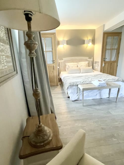 Chambre élégante au Le Paddock B&B à La Drenne avec lit blanc, tête de lit en rotin et lampadaire classique