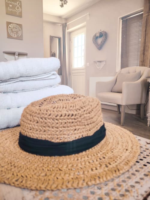 Chapeau de paille avec ruban noir posé sur le lit de la Chambre Légende au Paddock B&B, La Drenne