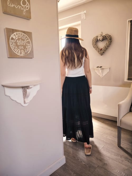 Femme au chapeau de paille et jupe noire dans la chambre Légende du gîte Le Paddock, décorée style côtier