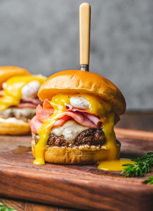 Burger gastronomique avec fromage fondant et bacon sur planche en bois à La Ferme aux Charmes, Solre-le-Château