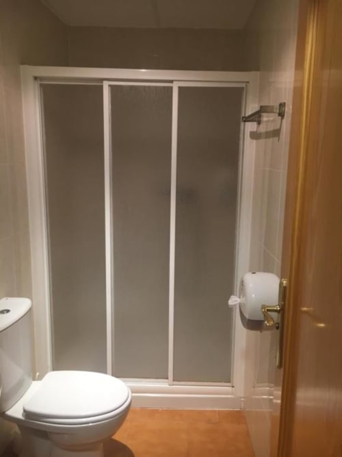 Baño moderno en el Hostal Imaginatelo con ducha de cristal, inodoro blanco y piso de cerámica en Carrascosa del Campo,
