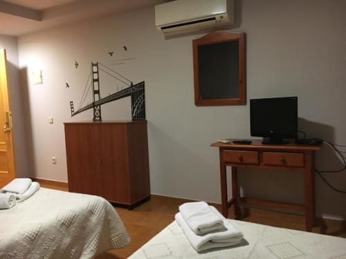 Habitación doble en Hostal Imaginatelo con dos camas, muebles de madera, escritorio con TV y arte mural del Puente Golden Gate