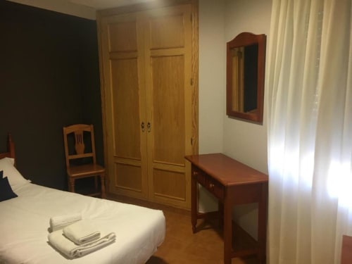 Habitación individual en Hostal Imaginatelo con cama, armario de madera, escritorio y espejo en Carrascosa del Campo