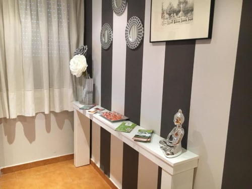 Habitación Deluxe en Hostal Imaginatelo con pared de rayas, mesita blanca, florero blanco y cuadros decorativos