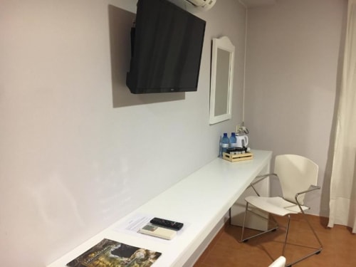 Escritorio de la habitación deluxe del Hostal Imaginatelo con TV mural, escritorio blanco, silla y espejo en Carrascosa del Campo