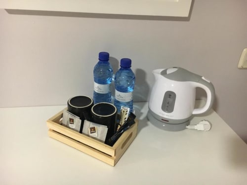 Amenidades de la habitación del Hostal Imaginatelo con hervidor eléctrico, botellas de agua y preparación de café en bandeja de madera