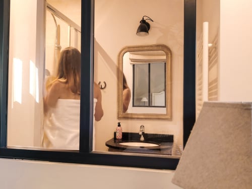 Salle de bain moderne du Le Paddock B&B à La Drenne avec miroir encadré, vasque noire et articles de toilette