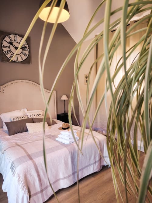 Chambre du Paddock B&B avec lit, horloge, lampadaire arc et plante décorativ à La Drenne, France