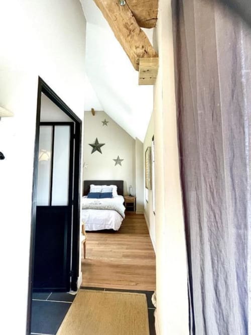 Entrée du couloir de la Chambre Chelsea au Le Paddock B&B avec porte noire, poutres en bois et vue du lit avec décoration murale étoilée
