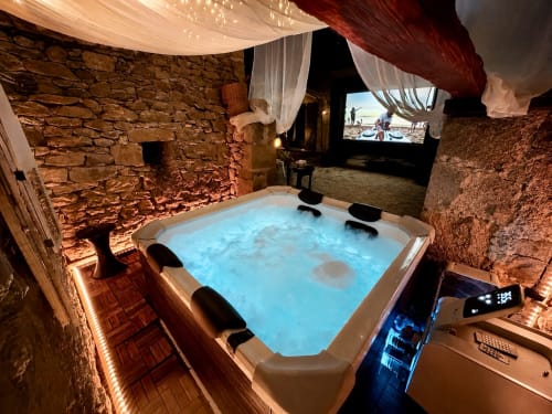 Jacuzzi luxueux aux eaux bleues illuminées dans suite spa cinéma au Domaine Valenquercy, à la campagne française