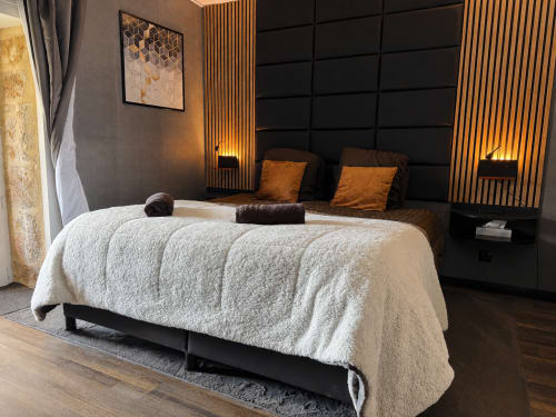 Suite de chambre luxueuse au Domaine Valenquercy avec lit matelassé crème, boiseries dorées, tête de lit noire et ambiance