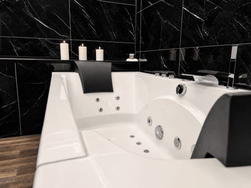 Baignoire balnéo de luxe avec jets d'eau et murs en marbre noir à la suite spa du Domaine Valenquercy au Vignon-en-Quercy