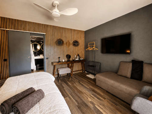 Suite luxueuse au Domaine Valenquercy avec lit, coin salon, TV écran plat, coiffeuse en bois et équipements spa