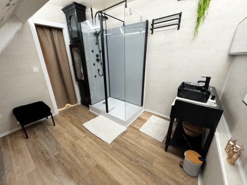 Modern bathroom at Domaine Valenquercy with corner shower, black vanity, heated towel rack, and wooden flooring in Le