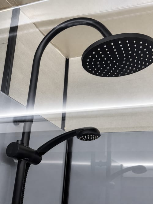 Black rainfall showerhead and handheld spray mounted on tiled shower wall at Domaine Valenquercy B&B in Le Vignon-en-Quercy