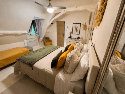 Cozy bedroom at Domaine Valenquercy with queen bed, mustard accents, ceiling fan, and garden views