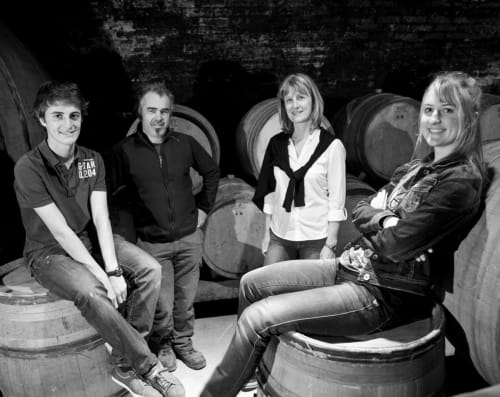 Quatre membres du personnel souriant dans la cave à vin du Domaine de Labrousse, gîte du Périgord