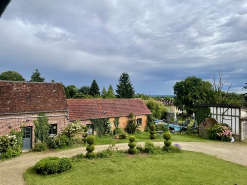 La cour du Paddock BnB à La Drenne avec ses bâtiments en brique, jardins soignés et vues sur la campagne