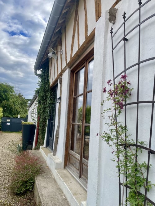 Façade du Paddock B&B avec clématites grimpantes, volets en bois et murs blancs à La Drenne