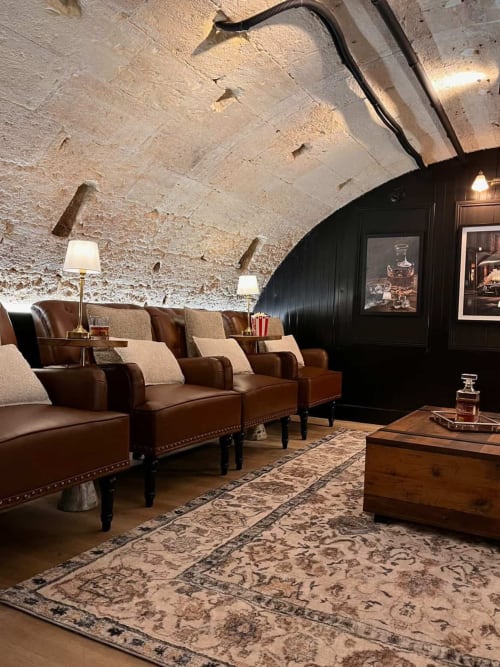 Luxurious private cinema room at Wellkhome Bordeaux with leather armchairs, stone ceiling, and elegant decor