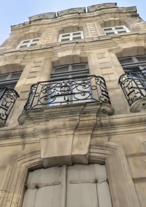 Classic Haussmann building facade in Bordeaux with ornate iron balconies and stone architecture