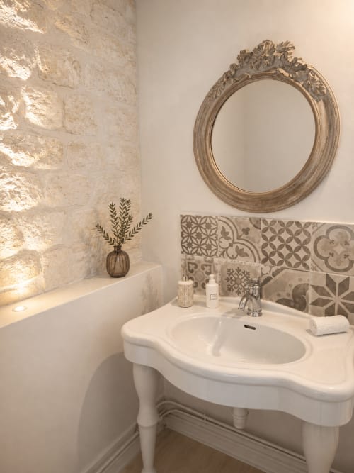 Salle de bains élégante à La Bastide Des Muriers avec lavabo sur pied, miroir orné et carrelage décoratif