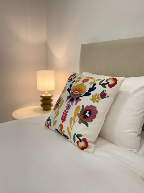 Cozy bedroom at In Casa Conciergerie villa in Figari with decorative floral pillow, white bedding, and brass bedside lamp