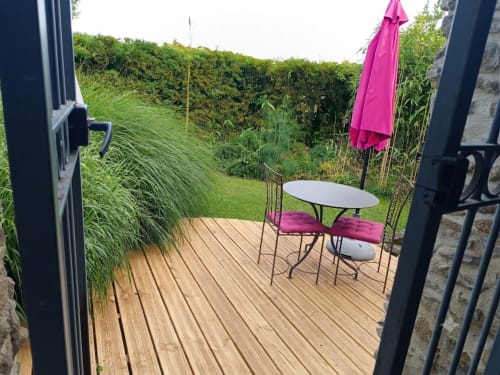 Terrasse privée de La Bastide Des Muriers avec terrasse en bois, parasol rose et salon de jardin