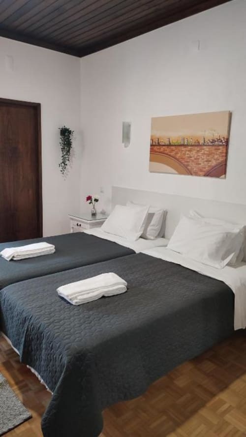 Dois leitos em quarto familiar moderno do Hotel Porta 80 House em Braga com travesseiros brancos e edredons escuros
