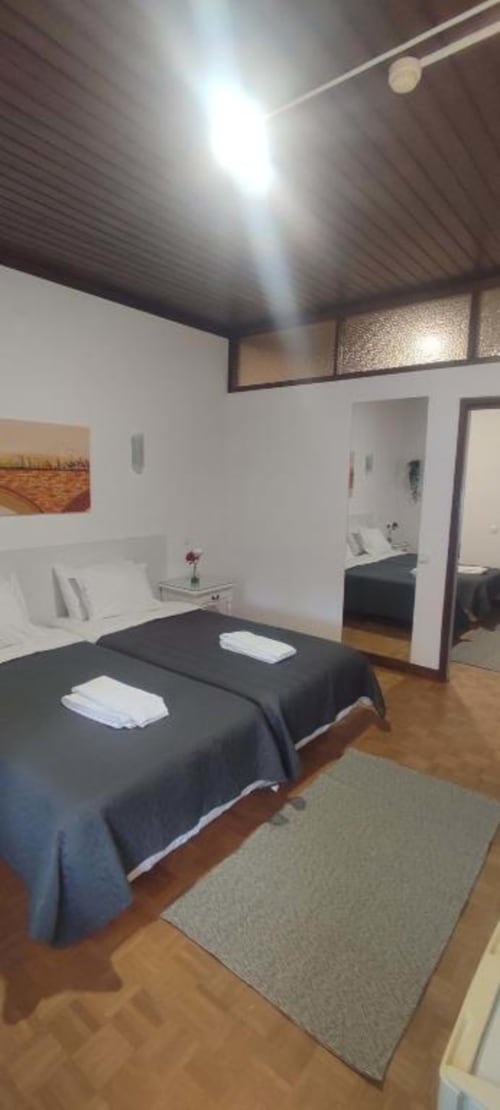 Bright modern twin bedroom at Porta 80 House in Braga with dark beds, white walls, wooden floor and mirrors