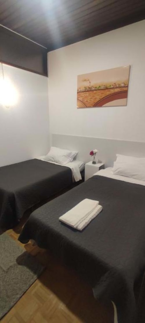Cozy twin bedroom at Porta 80 House hotel in Braga with two beds, white linens, artwork, and modern amenities