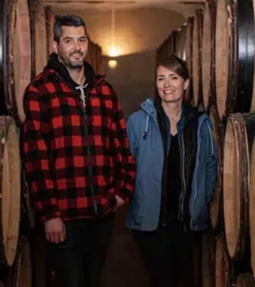 Deux hôtes souriants dans un couloir rustique du Domaine de Labrousse, un charmant gîte en Périgord, France.