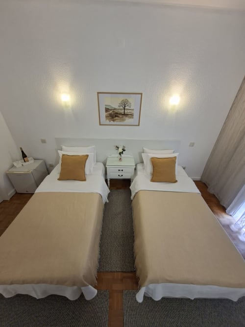 Twin bedroom at Porta 80 House Braga with two single beds, gold pillows, white bedding, and city view