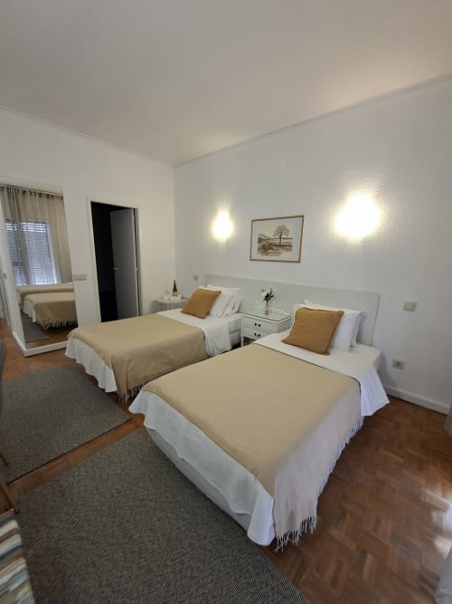 Twin bedroom at Porta 80 House Braga with two beds, modern lighting, and city view from terrace