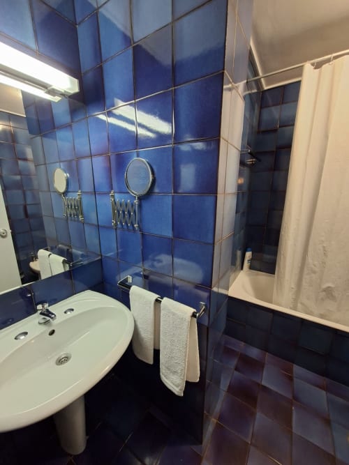 Modern bathroom at Porta 80 House hotel in Braga with blue tiled walls, white sink, mirrors, and shower area