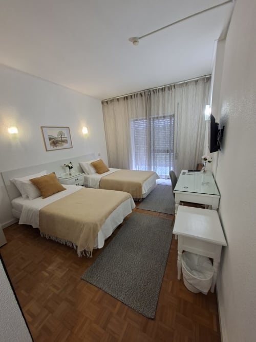Twin bedroom at Porta 80 House Braga with two beds, terrace view, TV, and modern amenities