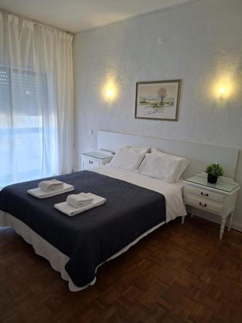 Quarto elegante da Porta 80 House em Braga com cama de casal, varanda com vista para a cidade e comodidades modernas
