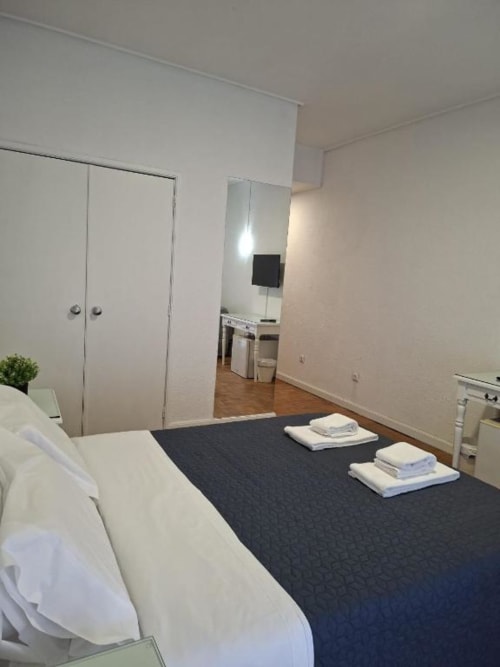 Quarto moderno da Porta 80 House Braga com cama de casal, tapete escuro, guarda-roupa e casa de banho privativa