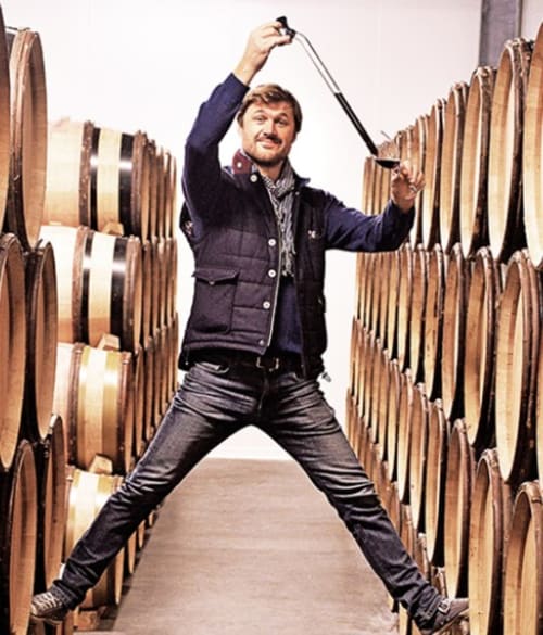Homme sautant entre les fûts de vin au Domaine de Labrousse, gîte en Périgord viticole