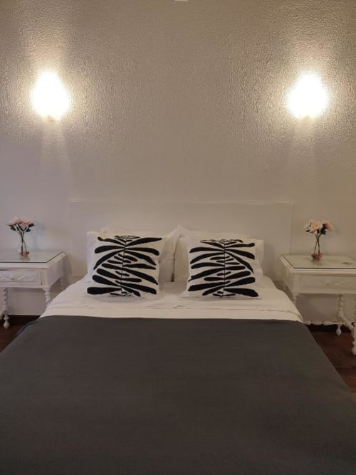 Quarto moderno do Hotel Porta 80 House em Braga com cama queen, almofadas com listras de zebra, cabeceira branca e iluminação ambiente