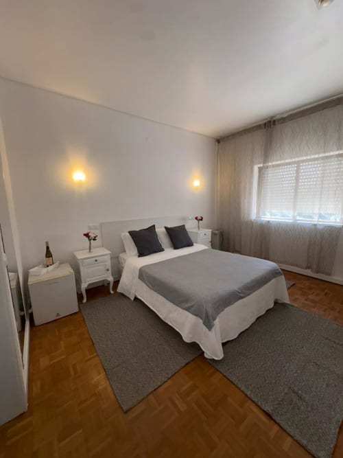 Modern bedroom at Porta 80 House Braga with queen bed, white nightstands, warm lighting, and wooden flooring
