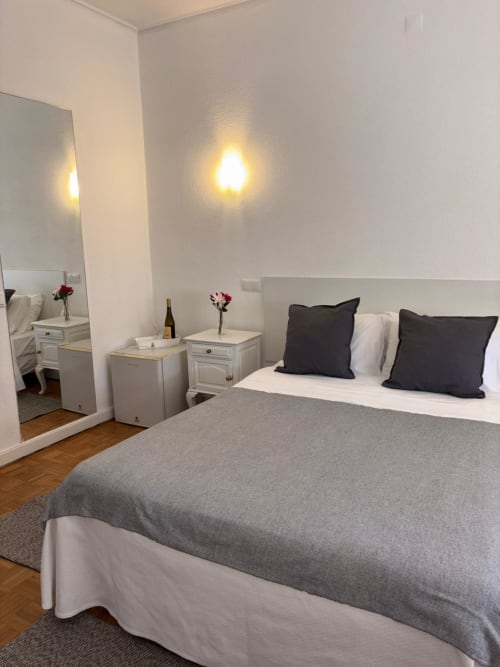 Modern hotel bedroom at Porta 80 House in Braga with queen bed, white bedside tables, mirror, and ambient lighting