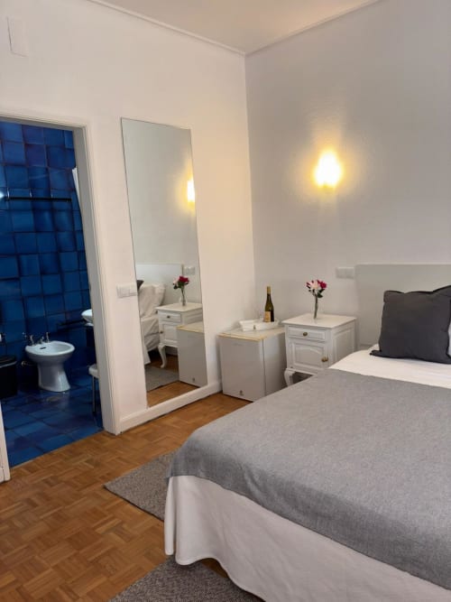 Porta 80 House Braga: Superior double room with bed, ensuite bathroom, mirror, nightstands with flowers, and wooden floors.