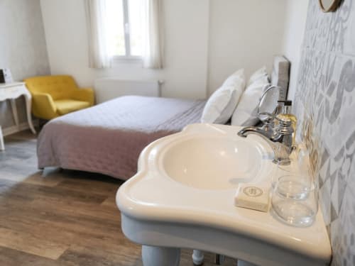 La chambre La Capitelle à La Bastide Des Muriers avec salle d'eau, lit et fauteuil jaune, Daux